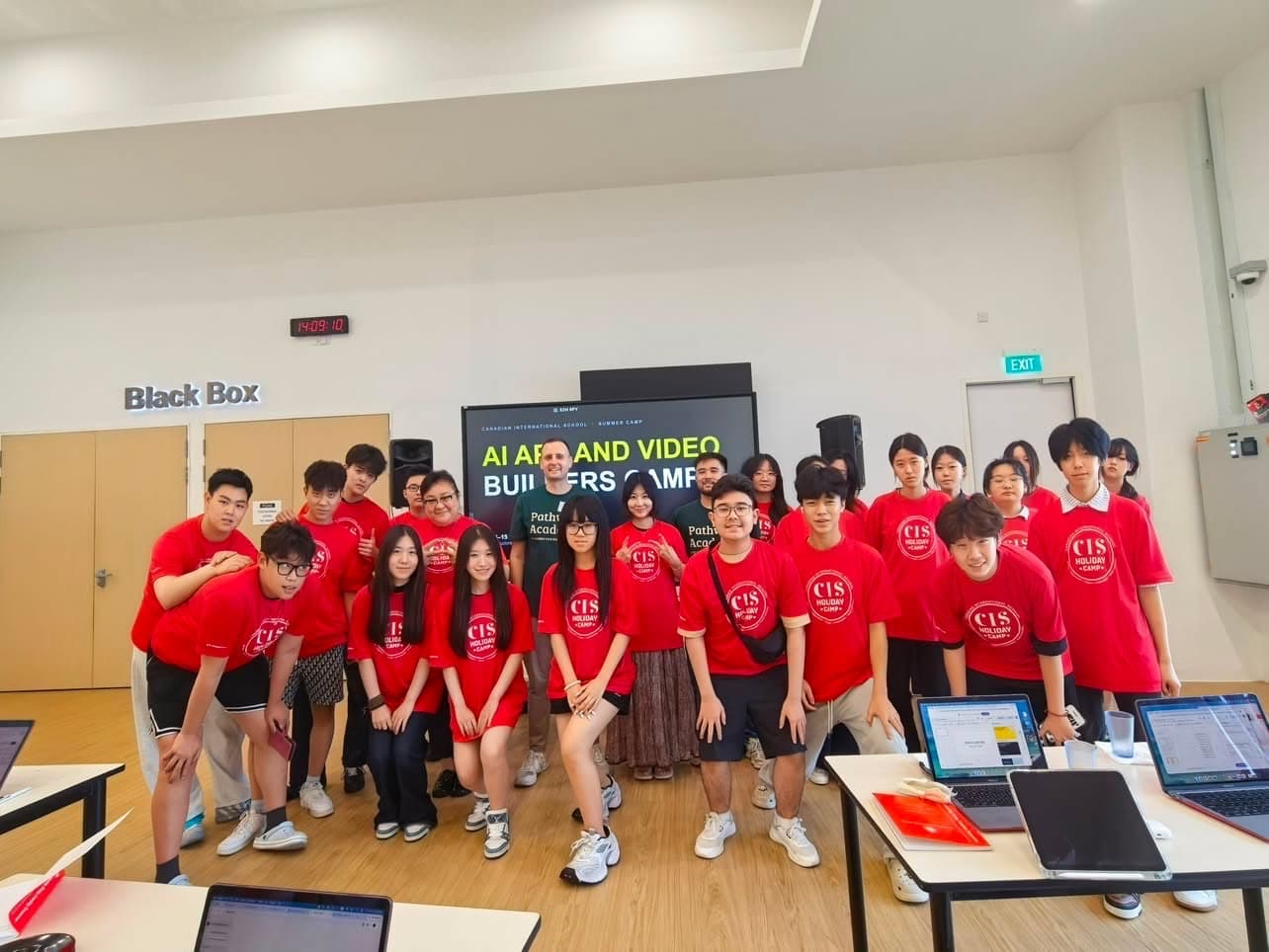 Students in matching camp t-shirts working at laptops during an AI Art and Video Builders camp