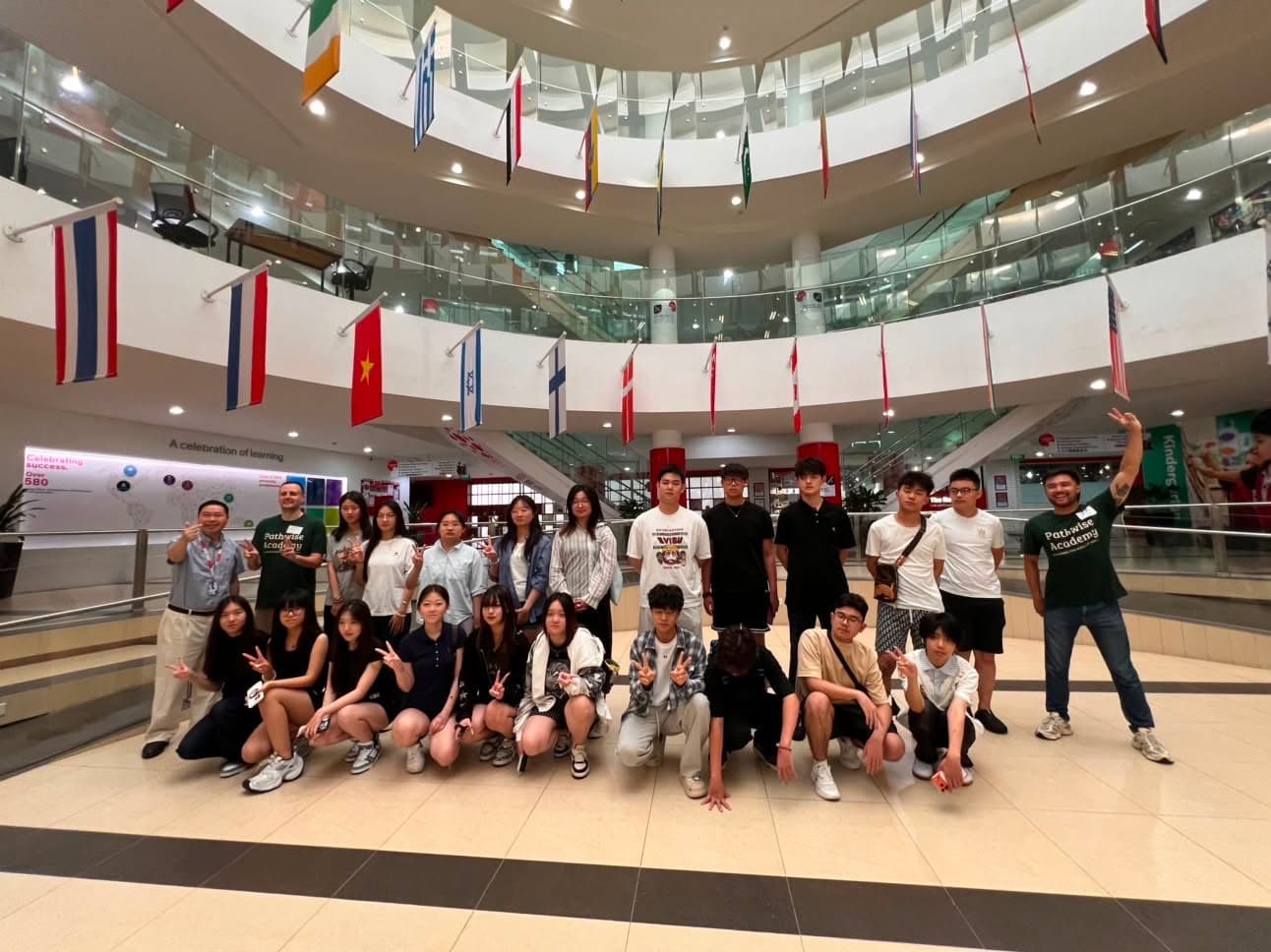 A young builder cohort posed together with their Pathwise instructor in a school atrium