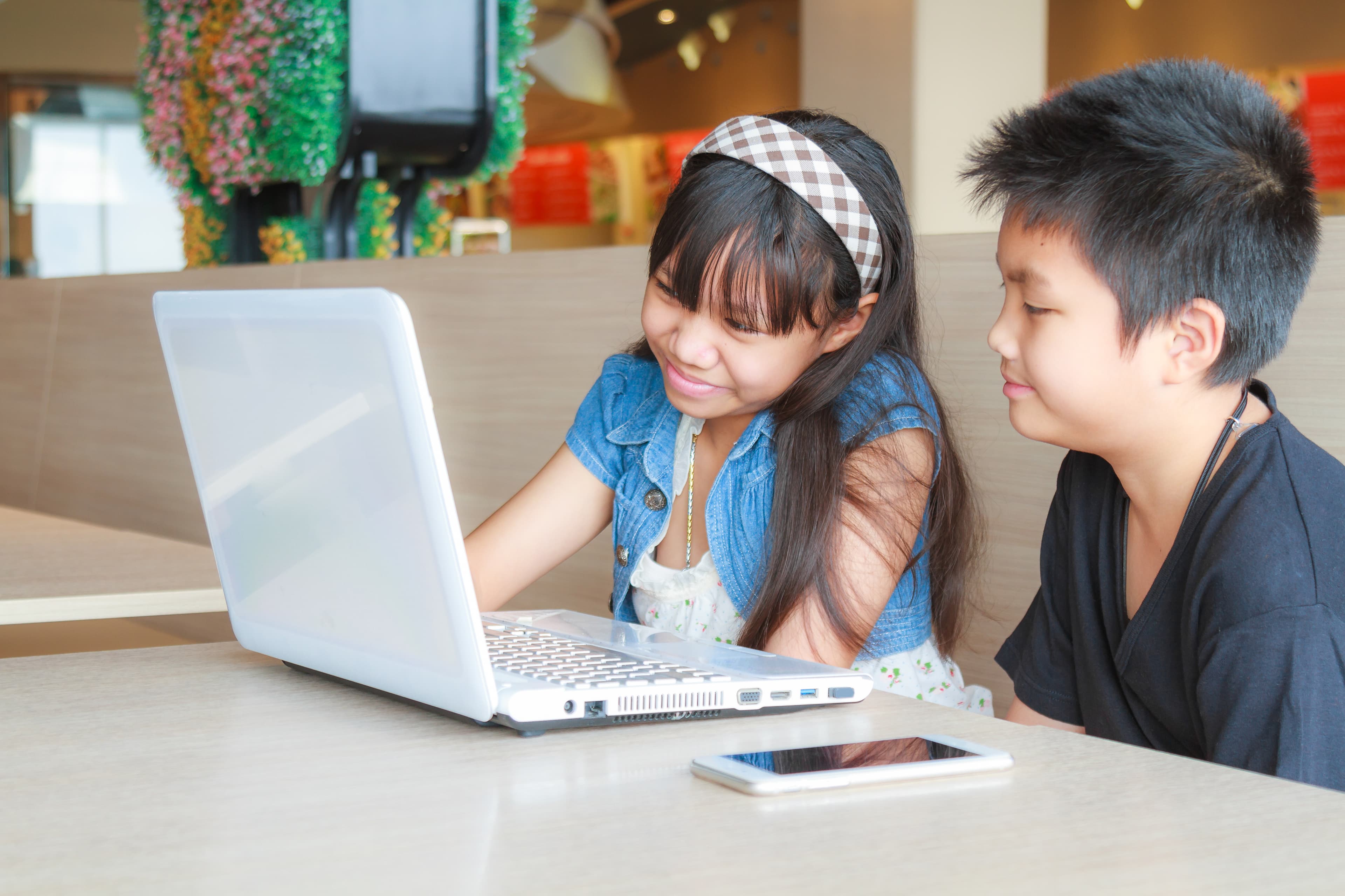Two young students collaborating on a laptop together